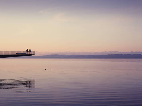 Couple walking on the pont de l'utopie on the shore of Neuchâtel lake.